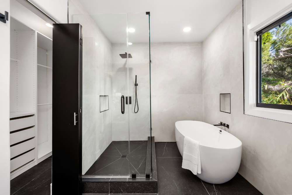 Renovated bathroom with a glass walk-in shower, wall niches and a freestanding bath
